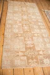 Perspective view of a distressed Kars runner showing its repeating geometric medallions and neutral palette.