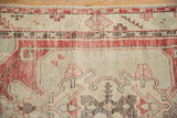 Distressed vintage Oushak rug showing faded red, ivory, and blue patterns with wear.