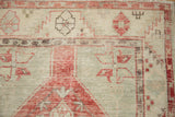 Distressed Oushak rug runner close-up: foundation wear, faded cherry red, seafoam geometric motifs.