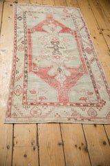 Distressed Oushak runner corner with faded cherry red serrated leaf border and ivory wear.