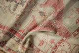 Distressed texture of a vintage Oushak runner with faded cherry red and ivory patterns.