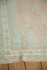 The evenly worn low pile and seafoam green border of a vintage distressed Oushak square rug.