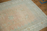 Evenly worn knot heads on a distressed Oushak rug in pale melon and seafoam green.