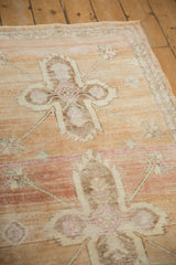 Worn texture of a distressed Oushak rug, with sandalwood abrash and pale magenta blossoms.