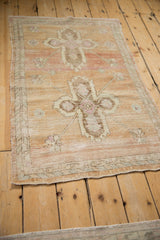 Distressed Oushak rug detail: heavily abrashed ground, pale magenta blossoms, and narrow borders.