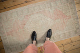 Faded blush and ivory hues on a distressed vintage Oushak runner's geometric design.