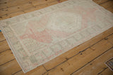 Distressed Oushak rug runner texture with faded blush, ivory, and silver patterns.