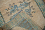 Hand-knotted reverse of vintage Oushak rug with blue selvage and distressed floral pattern.