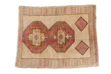 Vintage distressed Kars rug with offset hexagonal medallions in fuchsia and brown on a beige field.