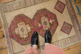 For-scale view of a distressed Kars rug with interconnected hexagonal medallions in brown and magenta.
