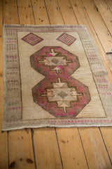 Angled perspective of a vintage distressed Kars rug with fuchsia and brown geometric medallions.