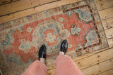A personal view of a distressed Oushak rug, showing its scale and soft brick red colors.