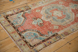Angled view of the distressed Oushak runner's medallion in brick red, dusty turquoise, and oxidized silver.