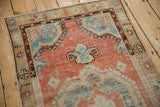 Corner detail of a distressed Oushak rug showing the worn floral border and spandrel.