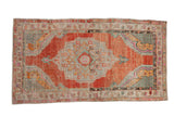 Vintage distressed Oushak rug with a central medallion, abrashed brick-red field, and silver, blue, and pink accents.