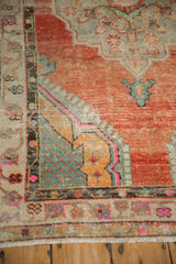 Corner spandrel on a distressed Oushak rug with bright pink, saffron, and slate blue accents.