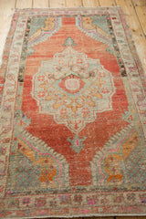 Angled view of the distressed Oushak rug, highlighting its abrashed brick red field and central medallion.