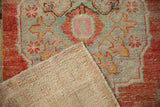 Folded corner of a vintage Oushak rug showing its hand-knotted foundation and distressed low pile.