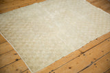 A distressed Tulu rug viewed from an angle, highlighting its checkered pattern and ivory tones.