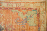 Distressed Oushak rug corner, serrated leaves in dusty cantaloupe and sea foam green.