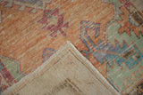 Vintage distressed Oushak rug corner reveals low pile, hand-knotted foundation, and faint reverse markings.