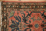 Corner of a vintage Persian rug showing its serpent border and hand-knotted texture.