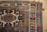 Corner detail of antique Caucasian rug, geometric blossoms, brick red, and foundation wear.