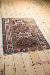 Antique Caucasian rug corner detail: geometric patterns, meandering borders, sapphire, brick red, ivory, and wear.