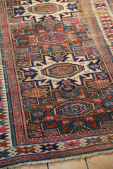 Antique Caucasian rug's geometric blossoms, starbursts, meandering vine border, teal, fuchsia, worn pile.