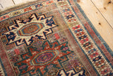 Antique Caucasian rug detail: geometric starbursts, meandering border, sapphire, fuchsia, brick, and pile wear.