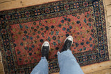 Vintage Persian Lilihan rug with dusty rose floral lattice and navy borders, shown underfoot.