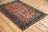 Vintage Lilihan rug corner: dusty blush field, navy double vine border with pinwheel flowers.
