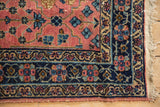 Vintage Lilihan rug corner: navy border with pinwheel flowers, dusty blush field, side cord.