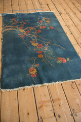 Vintage Art Deco rug's lower corner, featuring sky blue, orange, yellow blossoms, fringed end.