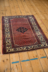 Angled view of a vintage Engelas rug, showing its brick red boteh pattern and navy diamond medallion.
