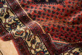 A vintage Engelas rug's hand-knotted pile, showing the red boteh field and ivory serpent wave border.