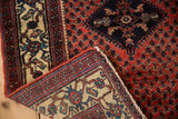 Folded corner of a vintage Engelas rug reveals the hand-knotted back and brick red boteh-patterned pile.