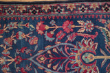 Corner detail of an antique Kerman rug with its dragon-style border and indigo blue floral pile.