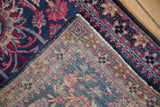 Folded corner of an antique Persian Kerman rug showing the detailed weave and hand-knotted foundation.