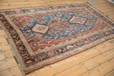 Angled view of an antique Qashqai rug showing its intricate triple medallions and Herati leaves.