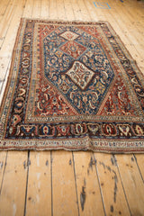 Antique Qashqai rug seen from an angle, highlighting its full length and geometric medallion pattern.