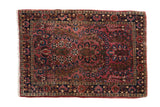 A fine vintage Sarouk rug mat with a dense floral bouquet on a raspberry red ground and dark navy border.