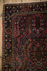 A navy blue border with gold and raspberry pinwheel florals on a vintage Sarouk rug.