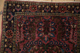 Intricate floral motifs in the navy blue border of a vintage raspberry red Sarouk rug.