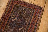 Close-up of vintage Belouch rug's rust red and cobalt geometric border with natural wear.