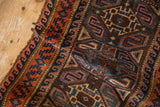 Detail of folded vintage Belouch rug, showing geometric serpent and seed border in blue and red.