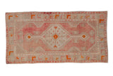 Vintage distressed Oushak rug runner with a geometric medallion in soft blush, ivory, and tangerine orange tones.