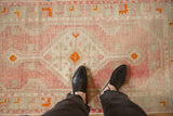 Overhead view of the softly worn pile of a vintage Oushak rug in blush and seafoam green.