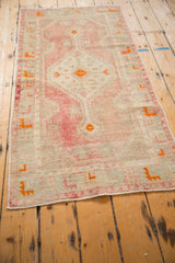 Angled view of a vintage Oushak runner showing its distressed, low pile in soft blush and ivory tones.