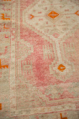 Low pile of a distressed Turkish rug showing abrashed rose and ivory with orange geometric details.